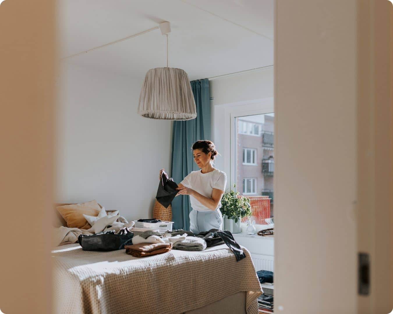 kvinne som bretter klær på sengen på soverommet